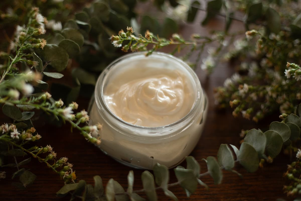 Open jar of whipped tallow balm surrounded by fresh eucalyptus